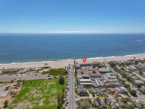 Vista aérea de una zona costera con playa, estacionamientos y edificios residenciales.