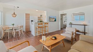 A modern living room with a dining area, a kitchen, and a TV.