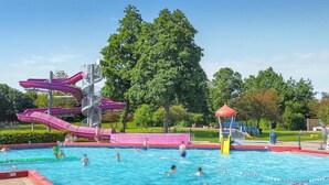 Una piscina con varias toboganes y una zona de juegos acuáticos.