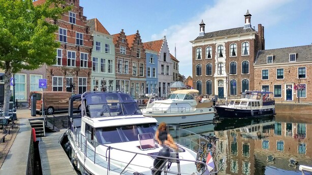 Un canal con barcos amarrados, rodeado de edificios históricos con arquitectura variada.