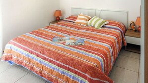 Ein ordentlich gemachtes Bett mit einem gestreiften Bettüberwurf, einem Kissen und einem kleinen Nachttisch mit Lampe und einer Dekoration.
