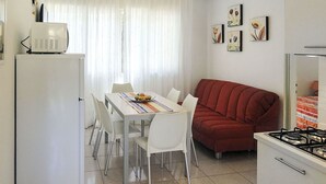 Eine kleine Küche mit Essbereich, einem roten Sofa und einem Kühlschrank.