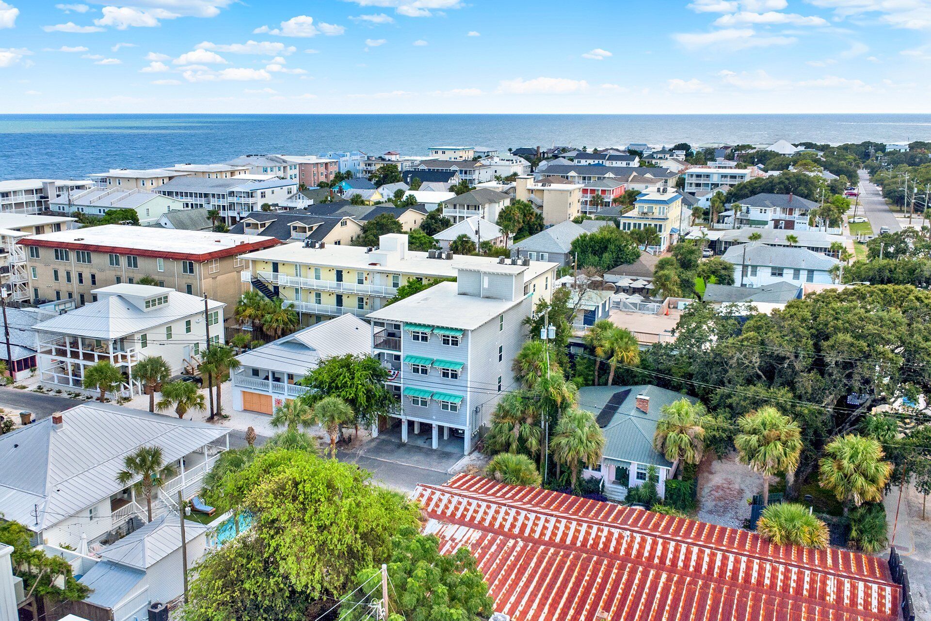 A coastal residential area with houses, some with balconies, and a view of the ocean.