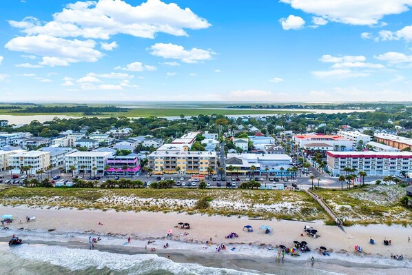 A coastal town with a beach, buildings, and a clear sky.