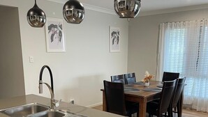 A modern kitchen with a central island, stainless steel appliances, and pendant lighting. - Modern Four Bedroom Holiday Home Available in Deebing Heights (Deebing Heights)
