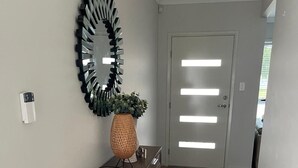 A hallway with a wooden bench, a decorative mirror, and a potted plant. - Modern Four Bedroom Holiday Home Available in Deebing Heights (Deebing Heights)