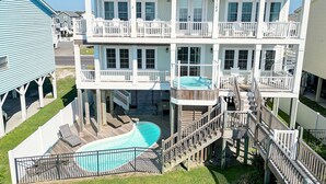 Una casa de varios pisos con piscina, balcones y una zona de terraza.