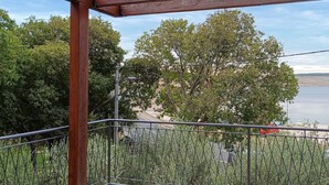 A balcony with a wooden pergola, metal railing, and a view of a tree-lined area with a body of water in the background. - 2 bedroom beautiful home in Modric (Modric)