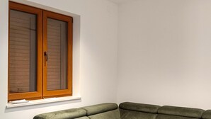 A corner room with a green sofa, a wooden-framed window, and a white wall. - 2 bedroom beautiful home in Modric (Modric)