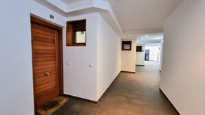 Un pasillo con una puerta de madera y un ventanal pequeño, que da a otra habitación.