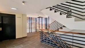 Una escalera moderna con barandilla de madera y pasamanos metálicos, que sube a un piso superior.