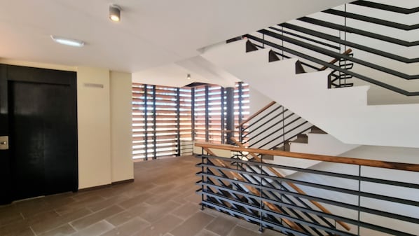 A modern staircase with a wooden handrail and metal railings, leading to an upper floor.
