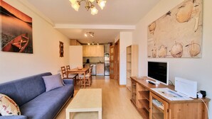 Un espacio habitable compacto con sofá, mesa de centro, televisor y un área de comedor con sillas y una mesa.