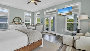 Ein geräumiges Schlafzimmer mit einem großen Bett, einem Deckenventilator und einem an der Wand montierten Fernseher.
