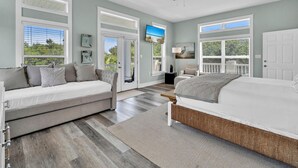 Ein Schlafzimmer mit Bett, Sofa, Deckenventilator und großen Fenstern.