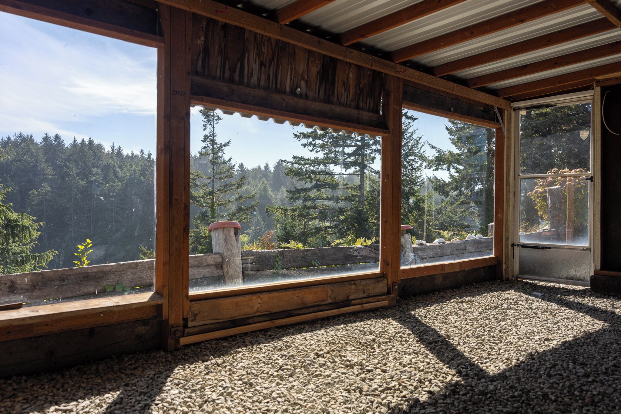 A room with large windows offering a view of a forested area.