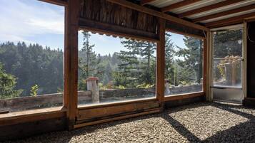 A room with large windows offering a view of a forested area.