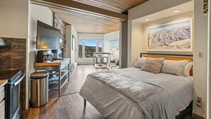 A modern hotel room with a large bed, a desk with a computer, a coffee machine, and a view of the mountains. - Ski-in/Ski-out, Covered Parking, Hot Tub! (Durango)