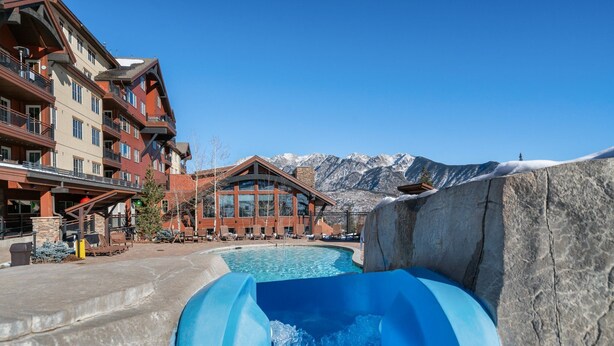 A hotel with a pool, a water slide, and mountains in the background. - Ski-in/Ski-out, Covered Parking, Hot Tub! (Durango)