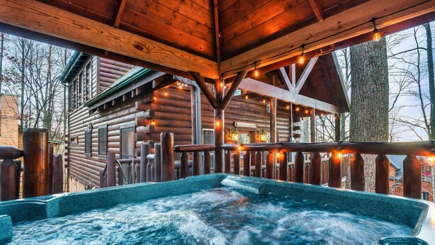 Een houten chalet met een hottub en lichtslingers.