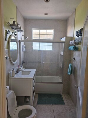 Baño con inodoro, lavabo, ducha y ventana.