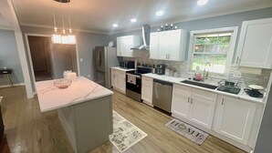 Una cocina moderna con armarios blancos, electrodomésticos de acero inoxidable y encimera de mármol.