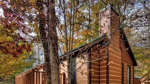 A cabin with a stone foundation, wooden exterior, and a deck. - Newly Built-Sleeps 8 w/Fire Pit, Arcade lineup, Hot Tub, Horseshoe Pit & BBall (Sevierville)