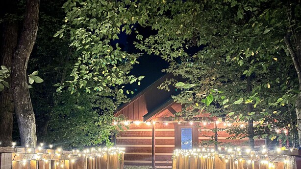 A wooden pathway leading to a building with string lights. - Newly Built-Sleeps 8 w/Fire Pit, Arcade lineup, Hot Tub, Horseshoe Pit & BBall (Sevierville)