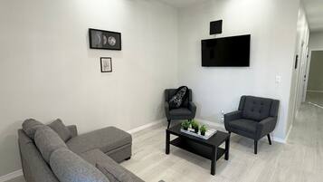 A modern living room with a sectional sofa, two armchairs, a coffee table, and a ceiling fan.