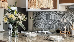 A kitchen with a granite countertop, a hanging woven light fixture, and patterned backsplash tiles. - Luxury Penthouse with Private Pool in Tulum by BT Homes (Tulum)