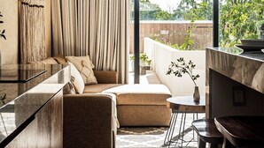 A modern living room with a sofa, a dining area with a table and chairs, a ceiling fan, and a large window with curtains. - Luxury Penthouse with Private Pool in Tulum by BT Homes (Tulum)