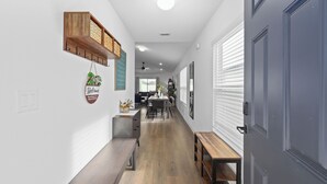 Un pasillo con un banco de madera, un letrero de bienvenida y una estantería de madera con letras.