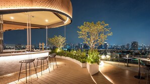 A rooftop bar with a curved seating area, a city skyline view, and a large perforated structure. - Somerset Sukhumvit 71 Bangkok (Bangkok)