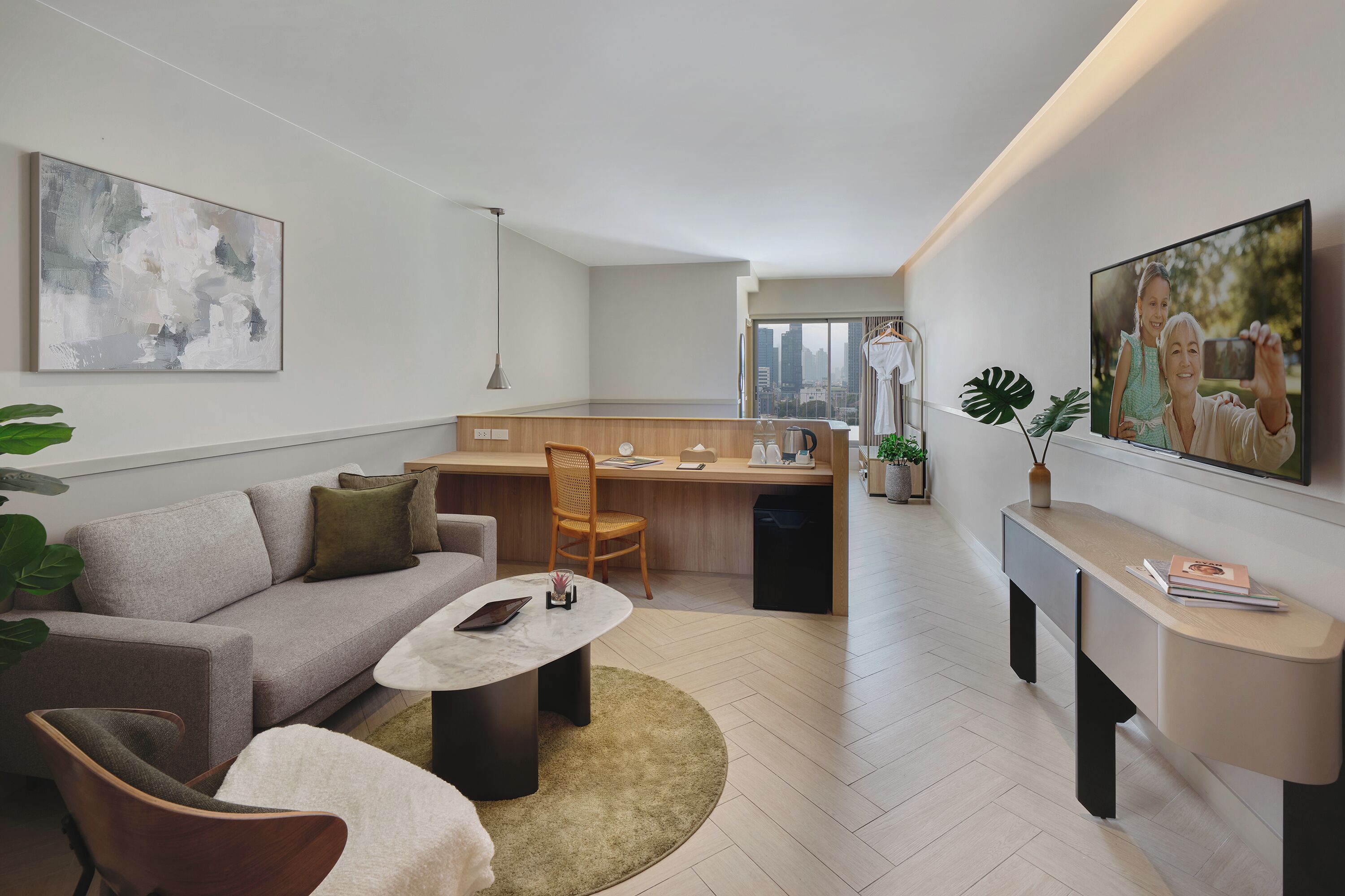 A modern living room with a sofa, coffee table, and a dining area with a kitchen in the background.