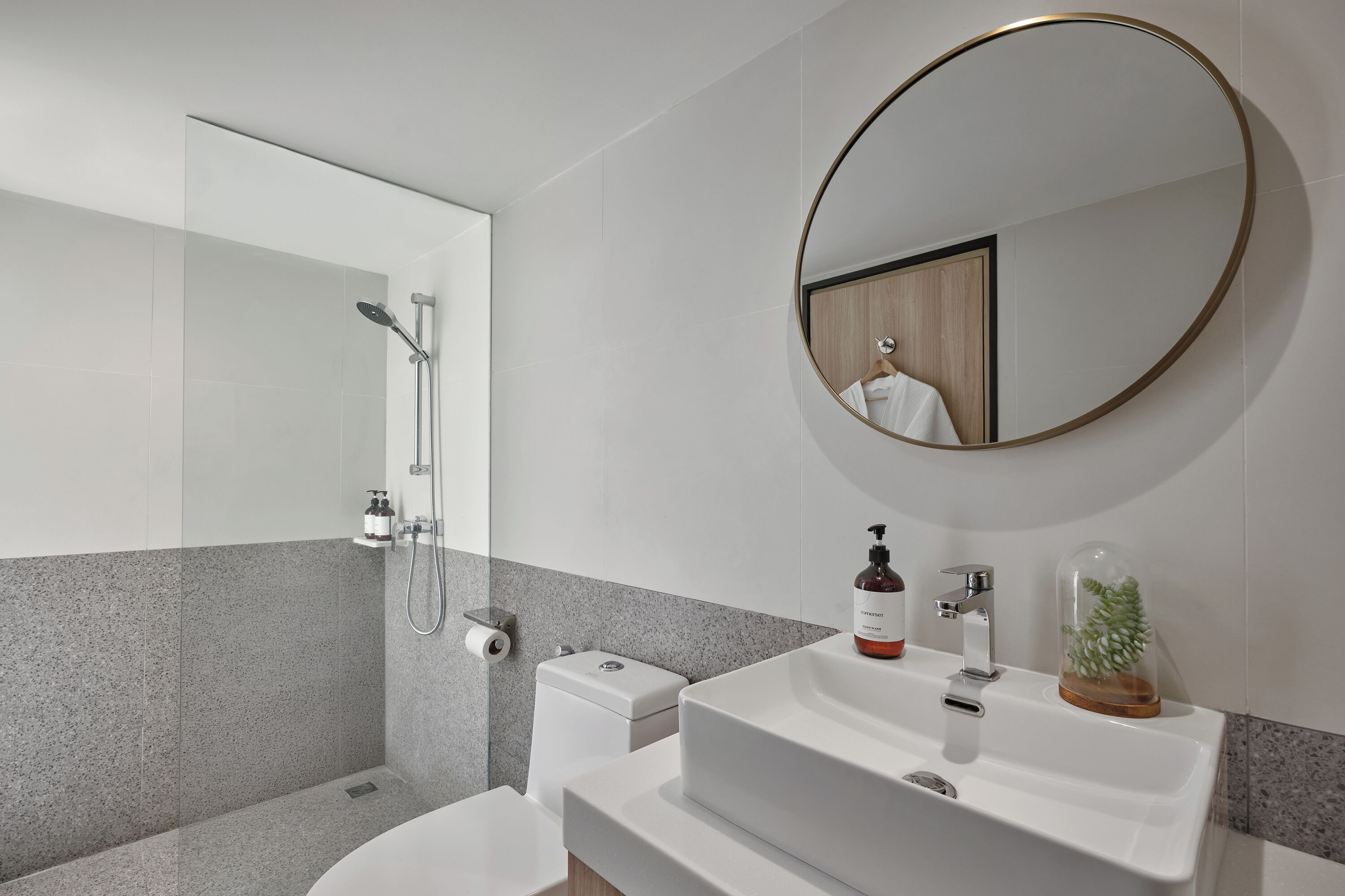 Ein modernes Badezimmer mit einer Duschkabine, einer Toilette, einem Waschbecken mit Spiegel und Pflegeprodukten.
