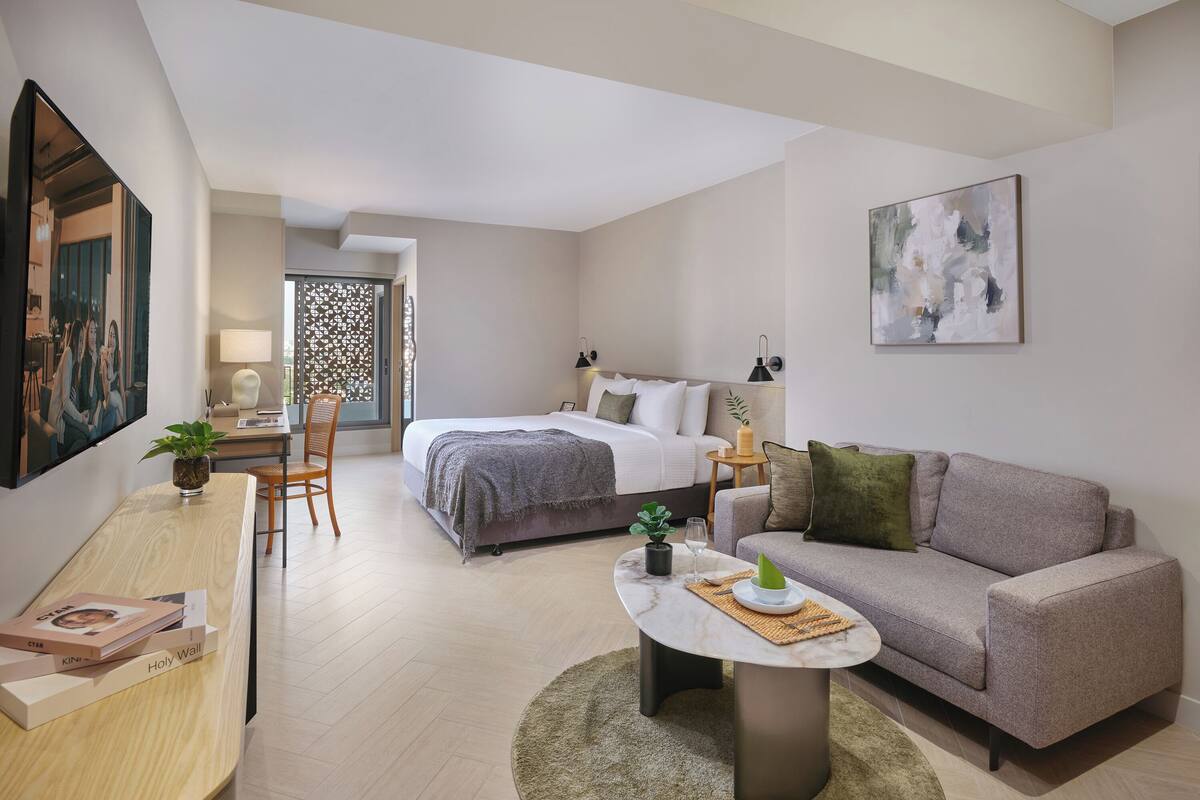 Una habitación de hotel moderna con una cama, un sofá, un escritorio y una mesita de centro.