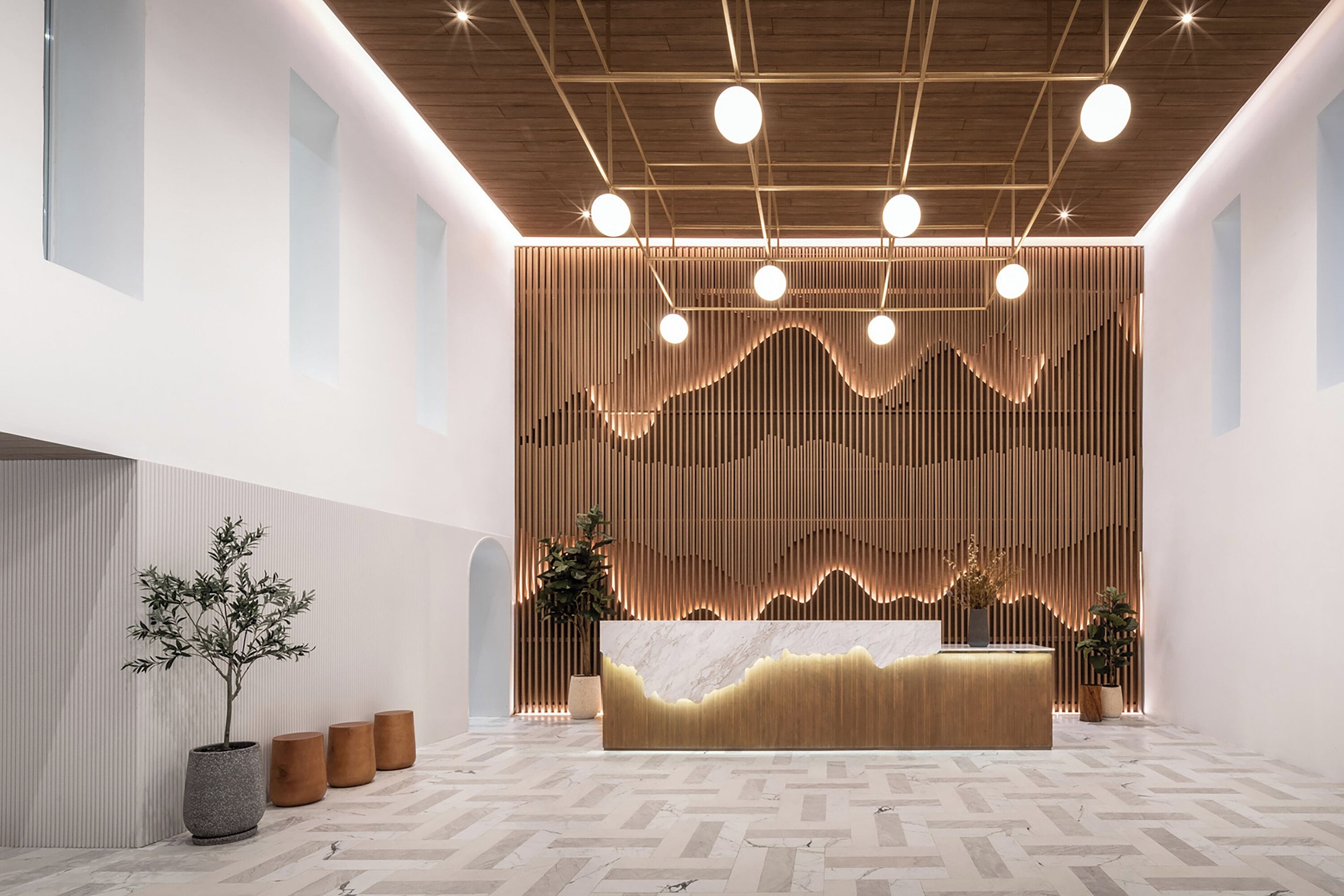 Un espace d’accueil moderne avec un comptoir de réception en bois, une plante en pot et un sol à motifs.