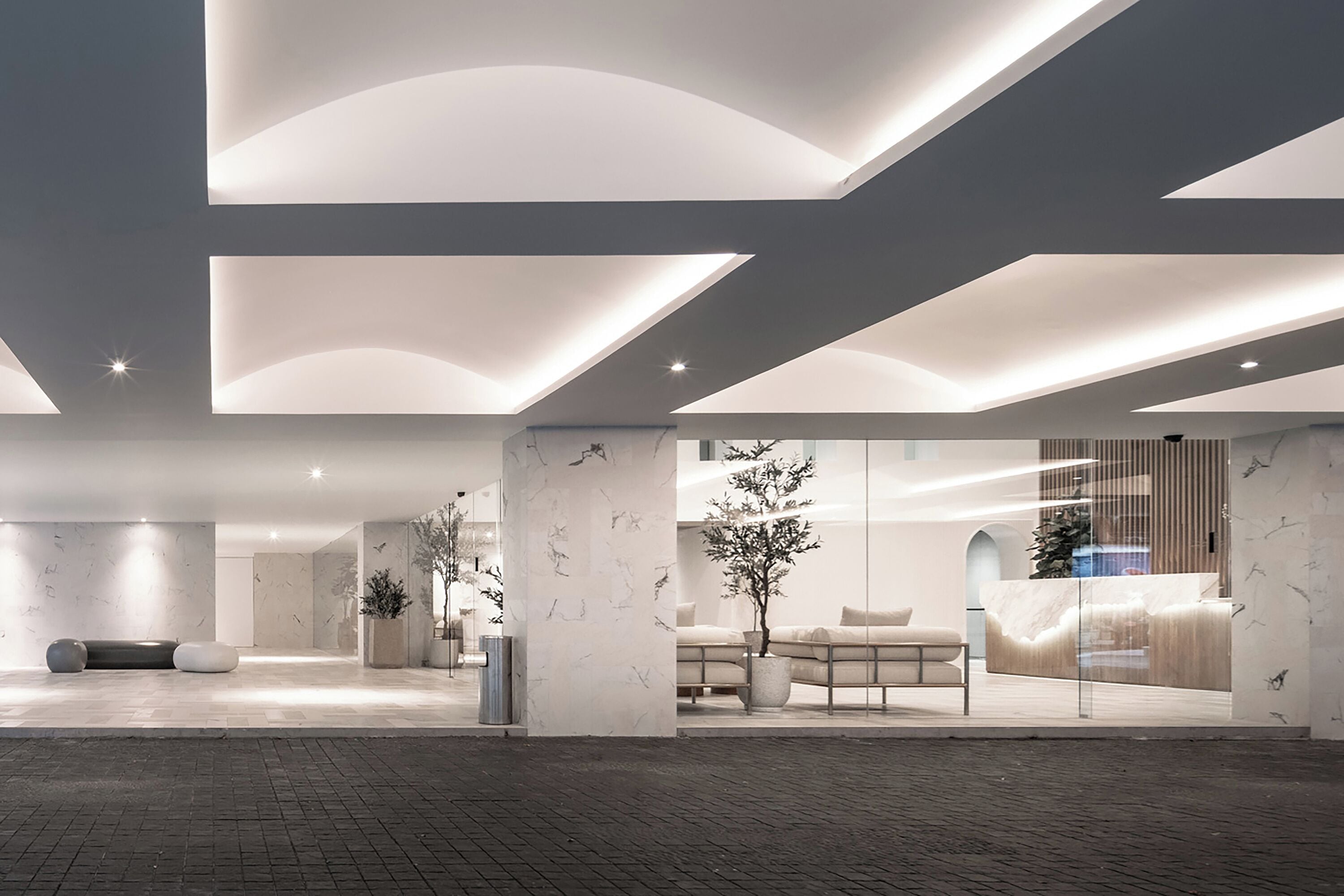 Een moderne lobby met een receptiebalie, een zithoek en een marmeren wand.