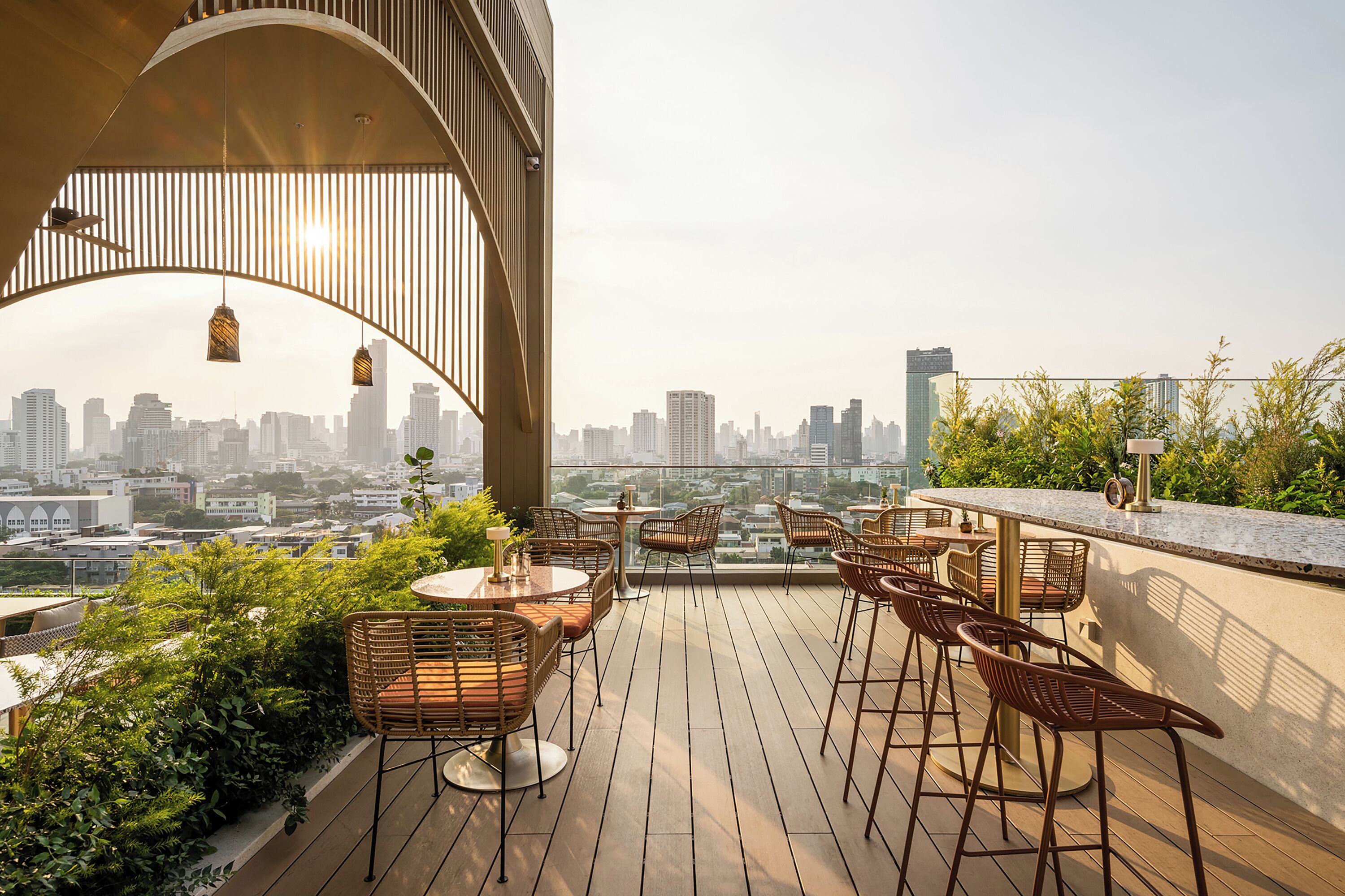 Un bar sul tetto con sedie e tavoli in vimini, affacciato su un panorama urbano.