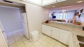 Una cocina con armarios blancos, encimera de granito y pileta de acero inoxidable.