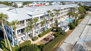 A multi-story hotel with balconies, a swimming pool, and a parking area. - Grand Caribbean East 101 2 Bedroom Condo (Destin)