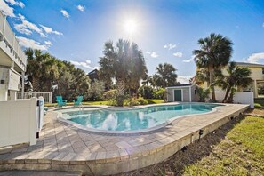 Relax by the pool surrounded by lush greenery and a paved deck.
