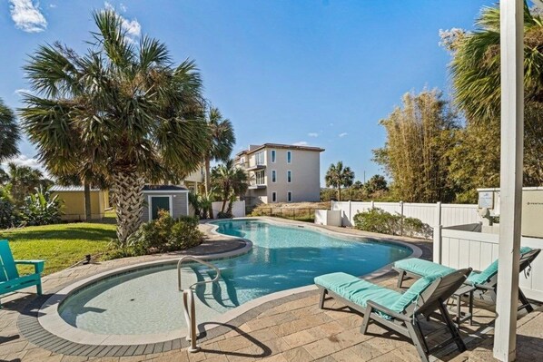 Relax by the pool surrounded by lush greenery and palm trees.