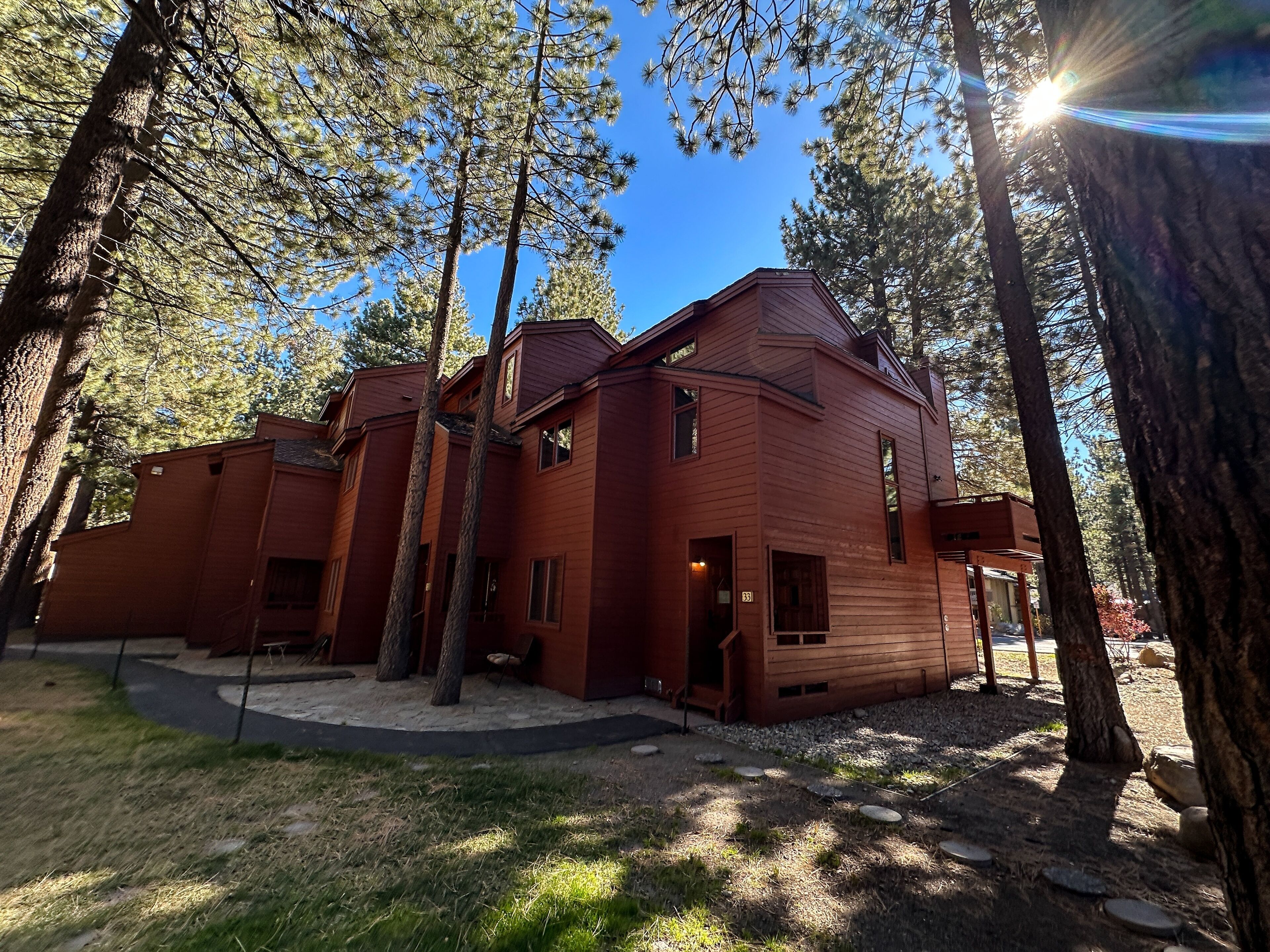 A red wooden building surrounded by tall trees, with a clear sky above.