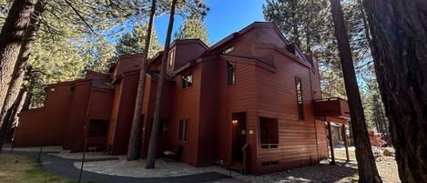 A red wooden building surrounded by tall trees, with a clear sky above.
