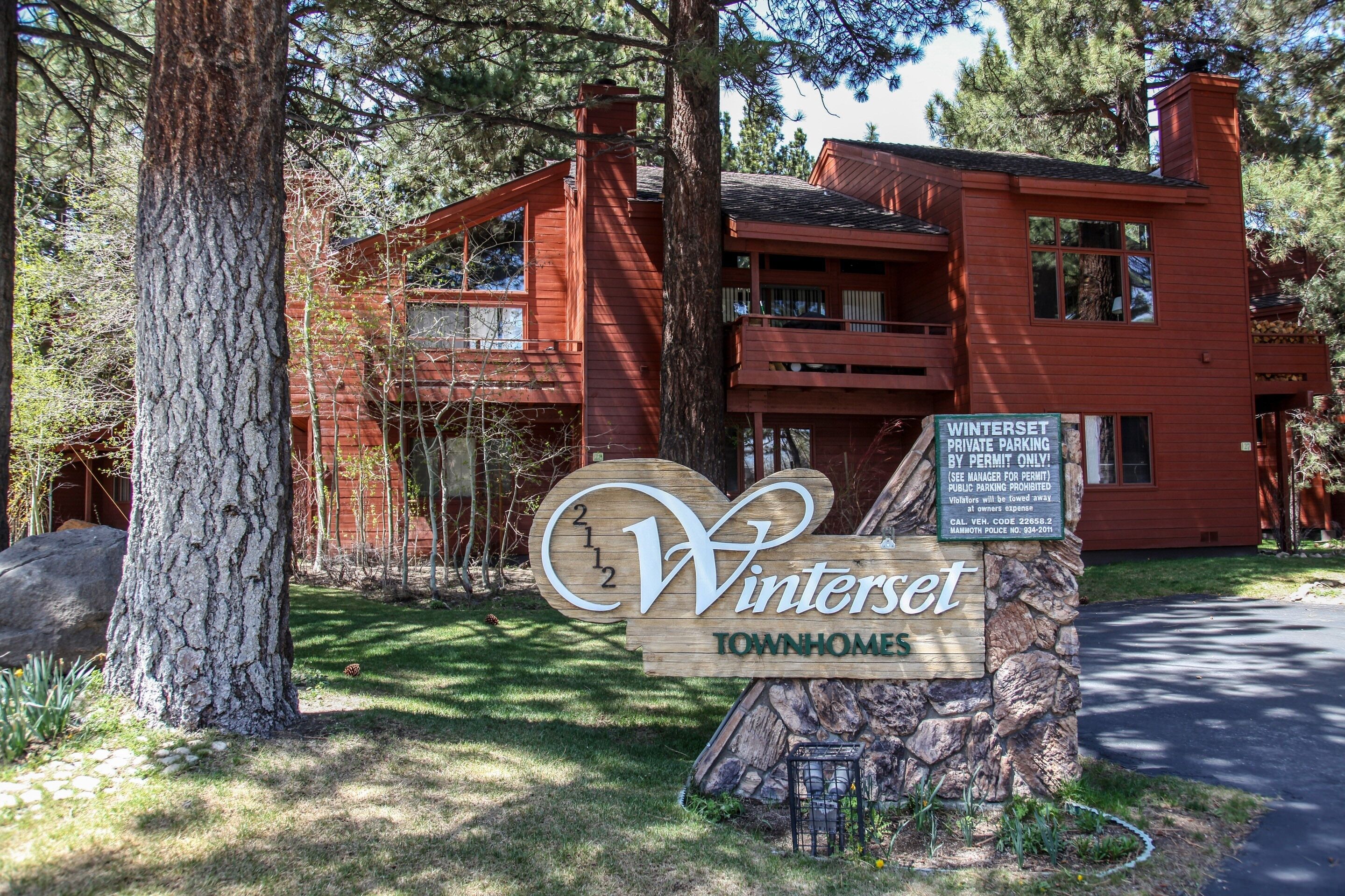 Uma placa de madeira com a inscrição 'Winterset Townhomes' e um aviso de estacionamento privado.