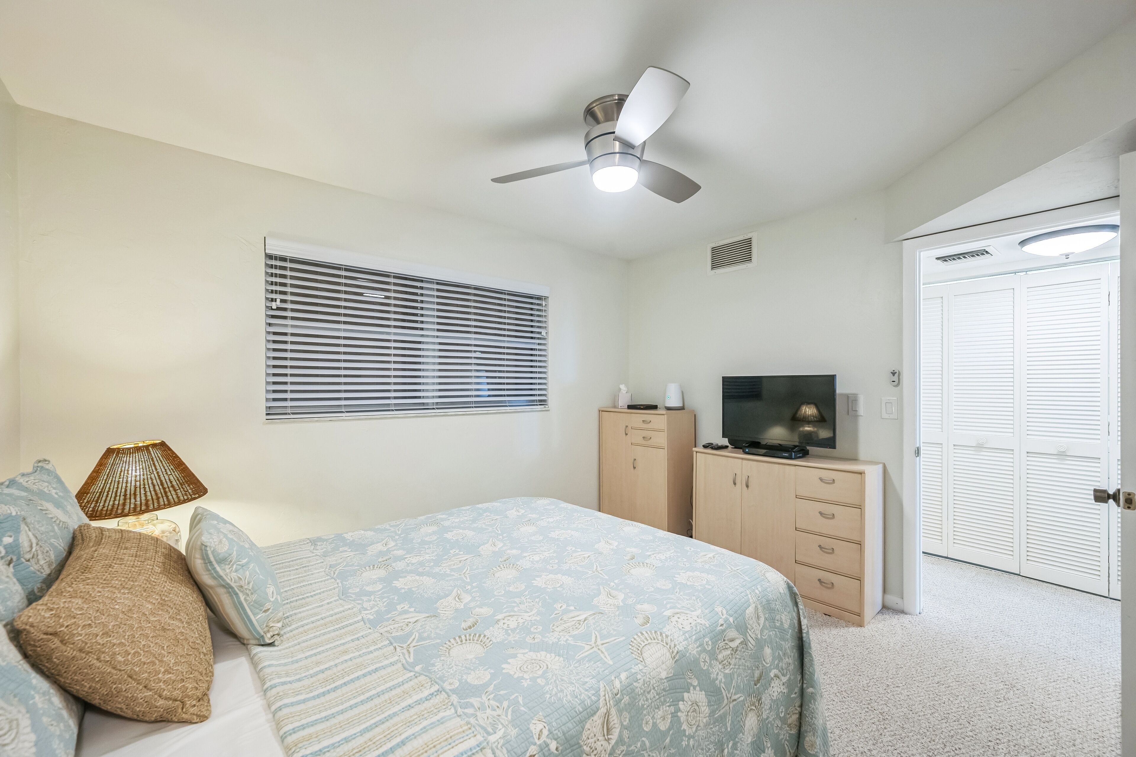 A bedroom with a bed, a dresser, a television, and a closet.