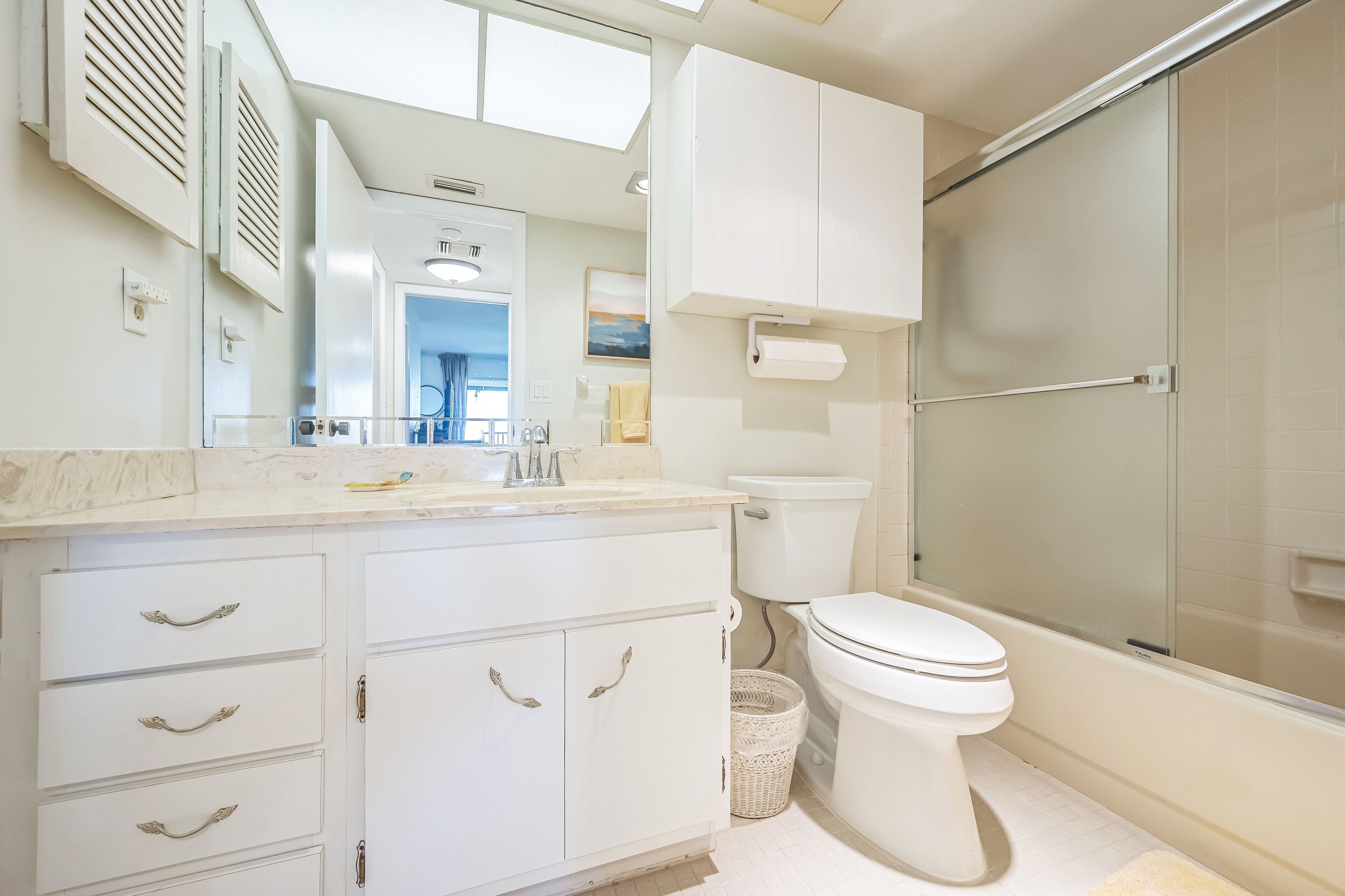 A modern bathroom with a toilet, shower, and vanity with drawers.