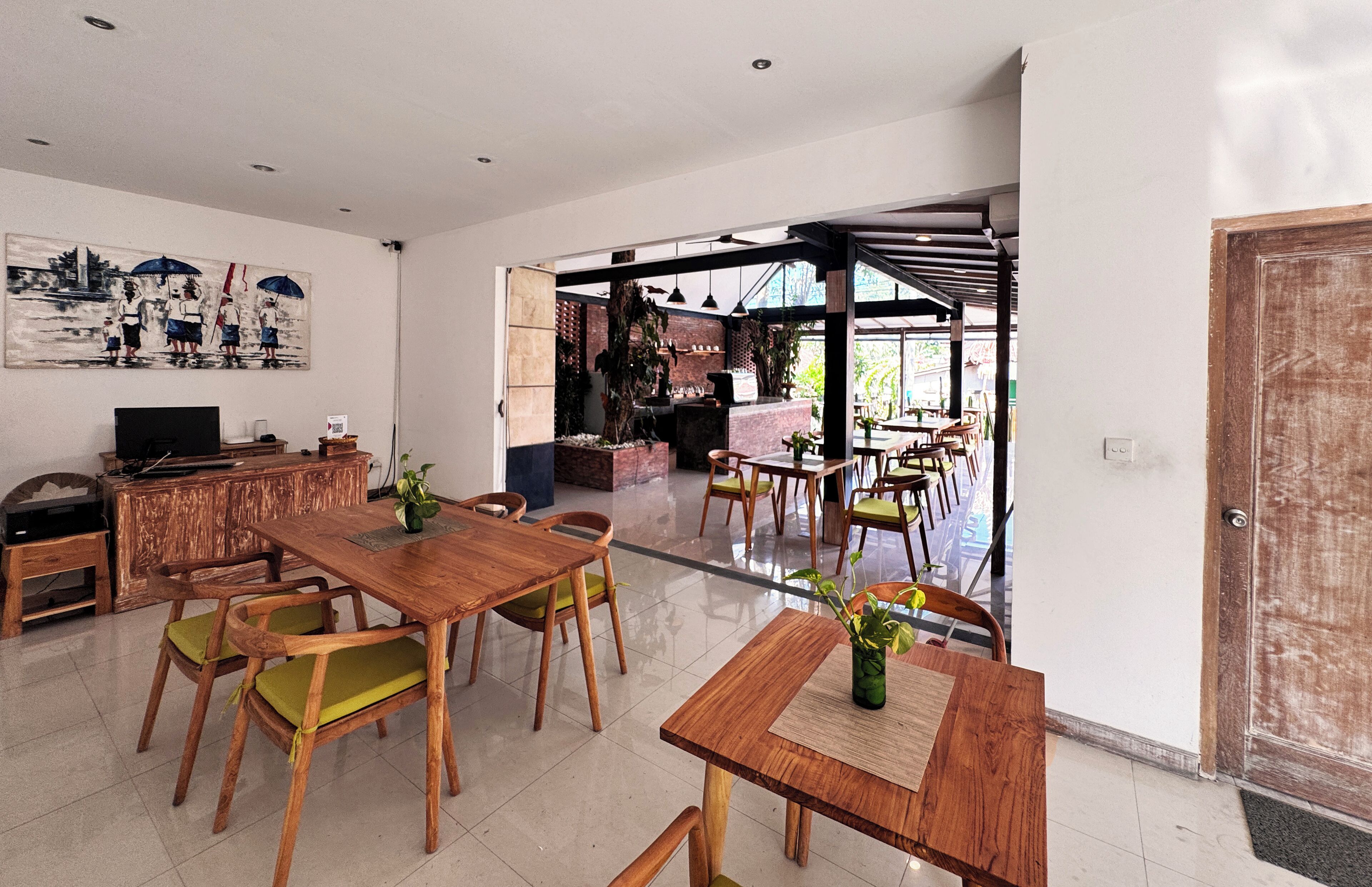 A spacious dining area with wooden tables and chairs, a television, and a painting on the wall.
