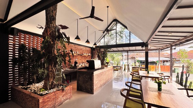 A modern restaurant with a brick wall, wooden furniture, and a large window overlooking the street. - Lubdhaka Canggu (Canggu)